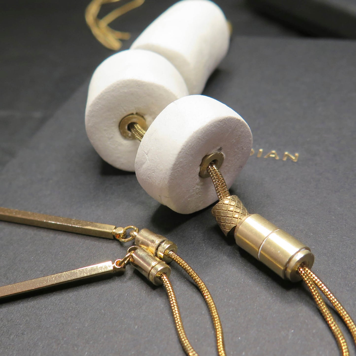 Stacked white stone tubular beads on adjustable gold snake chain necklace with brass detailing