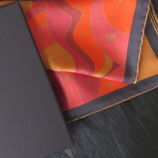 Pure silk scarf with a colorful abstract design in a black gift box on a textured surface