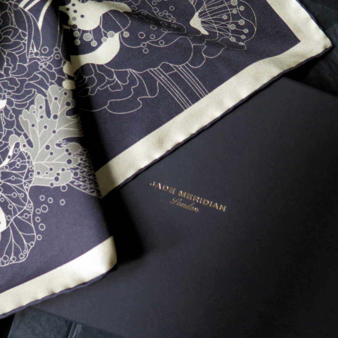 Pure silk scarf with hand rolled edge with a deep blue and white gold pattern on a bespoke black gift box with gold foil logo
