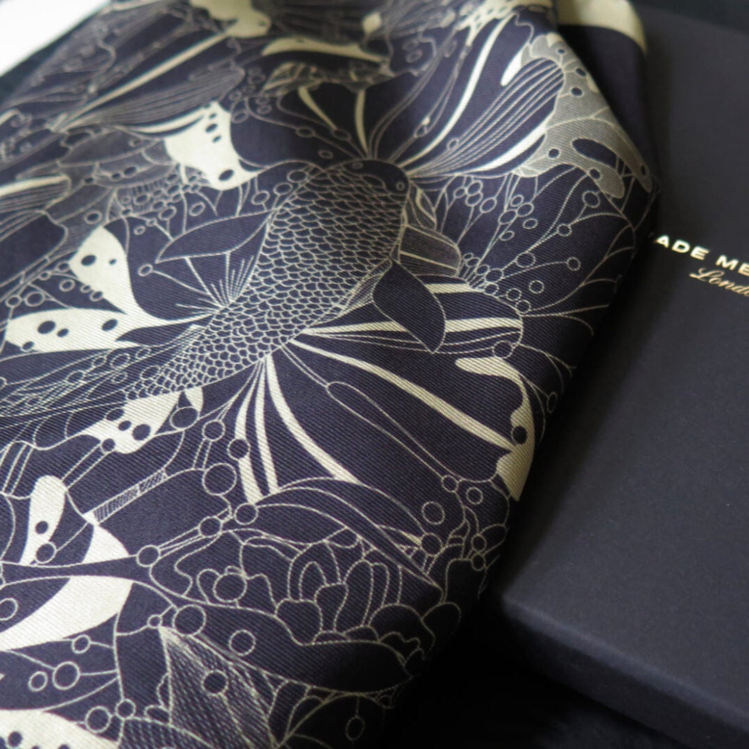 Pure silk scarf with hand rolled edge with a deep blue and white gold pattern on a bespoke black gift box with gold foil logo