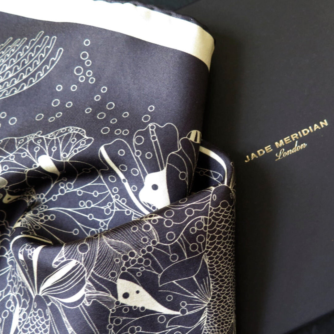Pure silk scarf with hand rolled edge with a deep blue and white gold pattern on a bespoke black gift box with gold foil logo