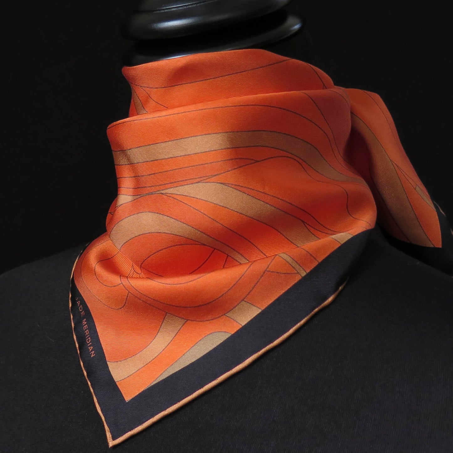 Image of orange and gold pure silk scarf with a dark border and hand-rolled bronze hem. Knotted around the neck, front view