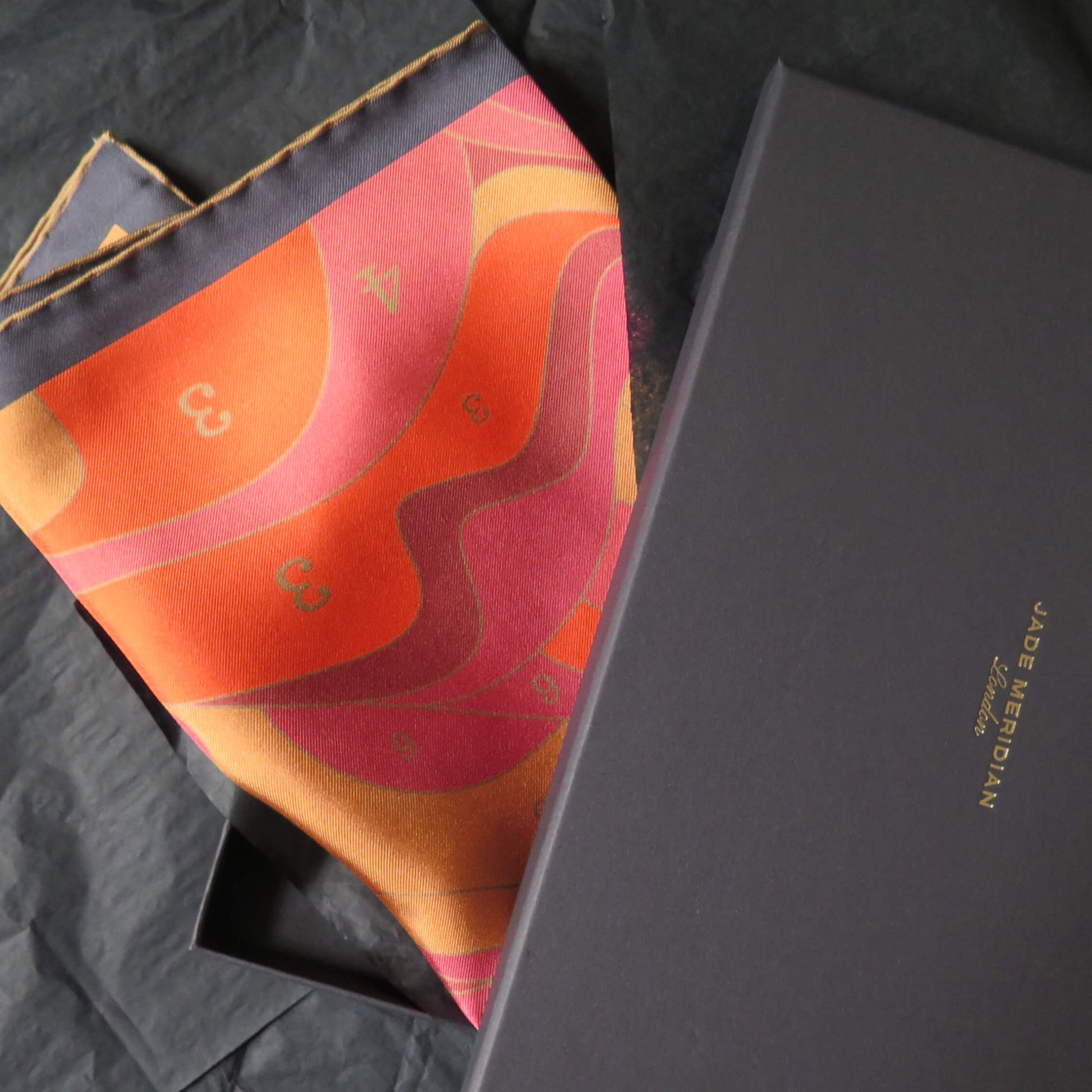 Pure silk scarf with an original colorful abstract design in a black gift box on a textured surface