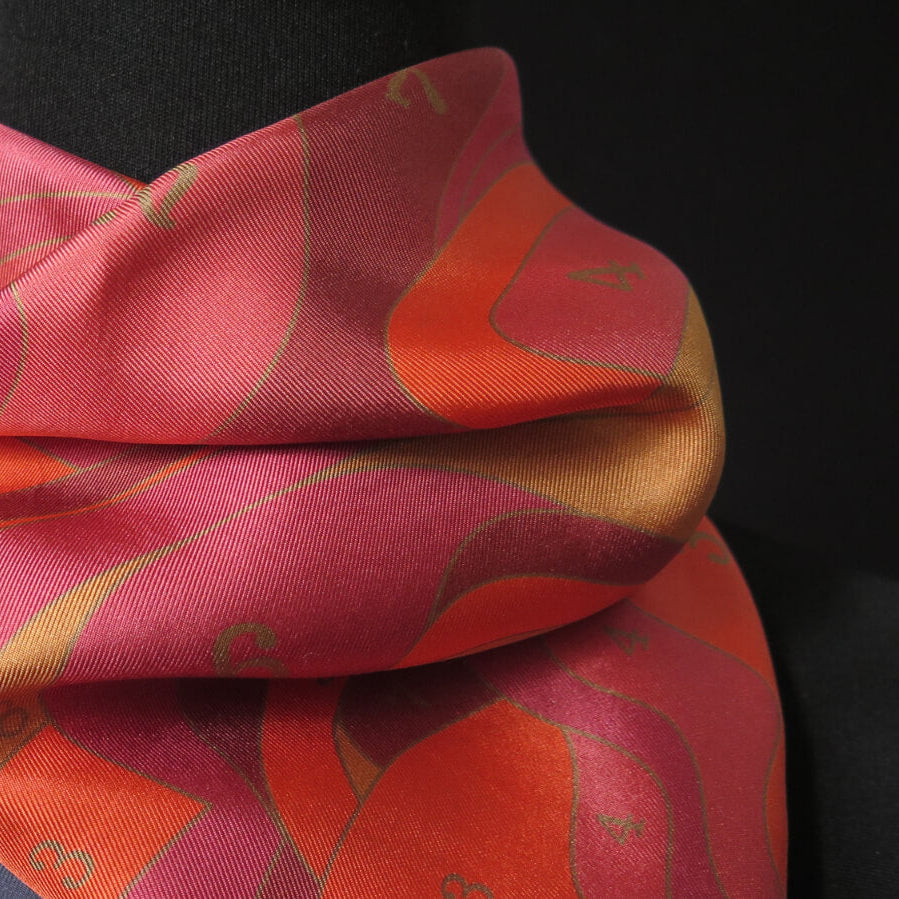 Pink, gold, ochre and orange patterned scarf on a black background